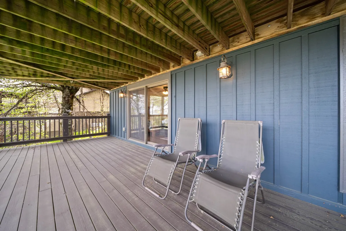 Two lounge chairs rest on a wooden deck with a blue accent wall, creating a serene space for outdoor relaxation. The setup invites guests to read a book, sip coffee, or enjoy the sunset in a calm, inviting setting.