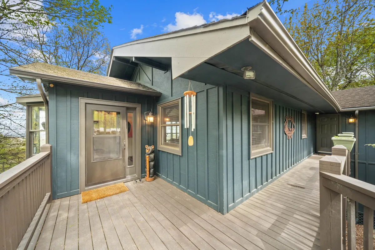 An inviting front entrance with a decorative wreath on the door, wind chimes, and sturdy wooden railing. The area is secure and welcoming, hinting at a safe and comfortable space for pets and families to settle in.