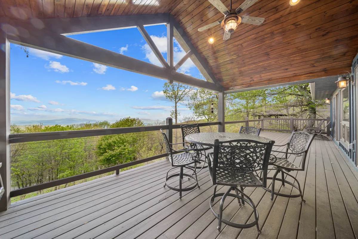 This image showcases an upper deck with a stylish outdoor dining set beneath a wooden ceiling, opening up to sweeping scenic views. The tranquil and inviting ambiance is perfect for morning coffee, sunset dinners, or gathering with friends and family while taking in the mountain panorama.