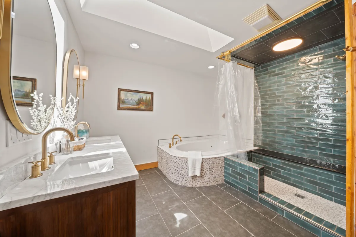 A luxurious bathroom with a freestanding soaking bathtub, double sink vanity, decorative mirror, and textured wall tiles. The space exudes tranquility and offers a spa-like experience.